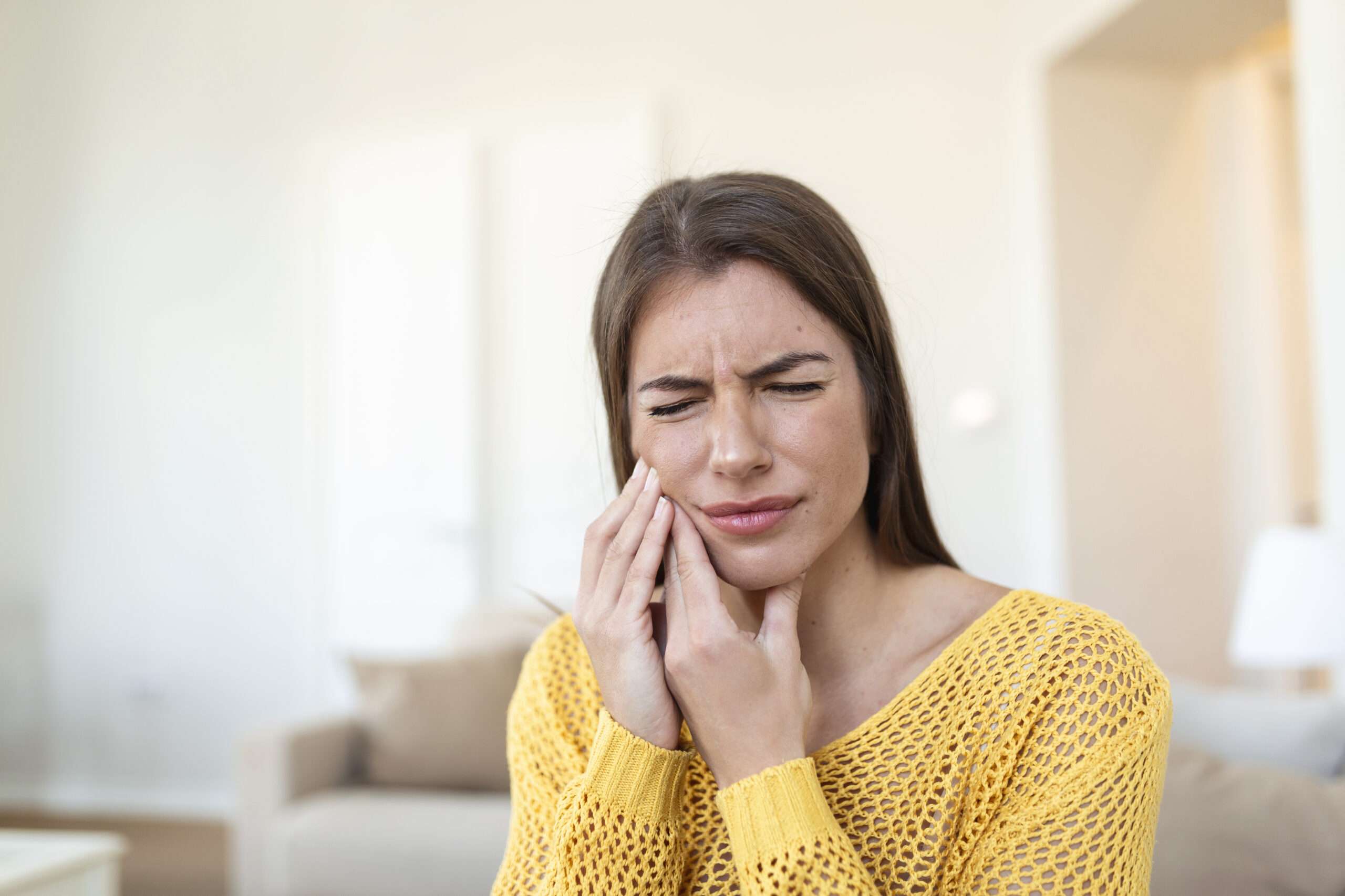 Persona con gesto de dolor en la mandíbula que podría estar relacionado con la articulación temporomandibular tratada en Adur
